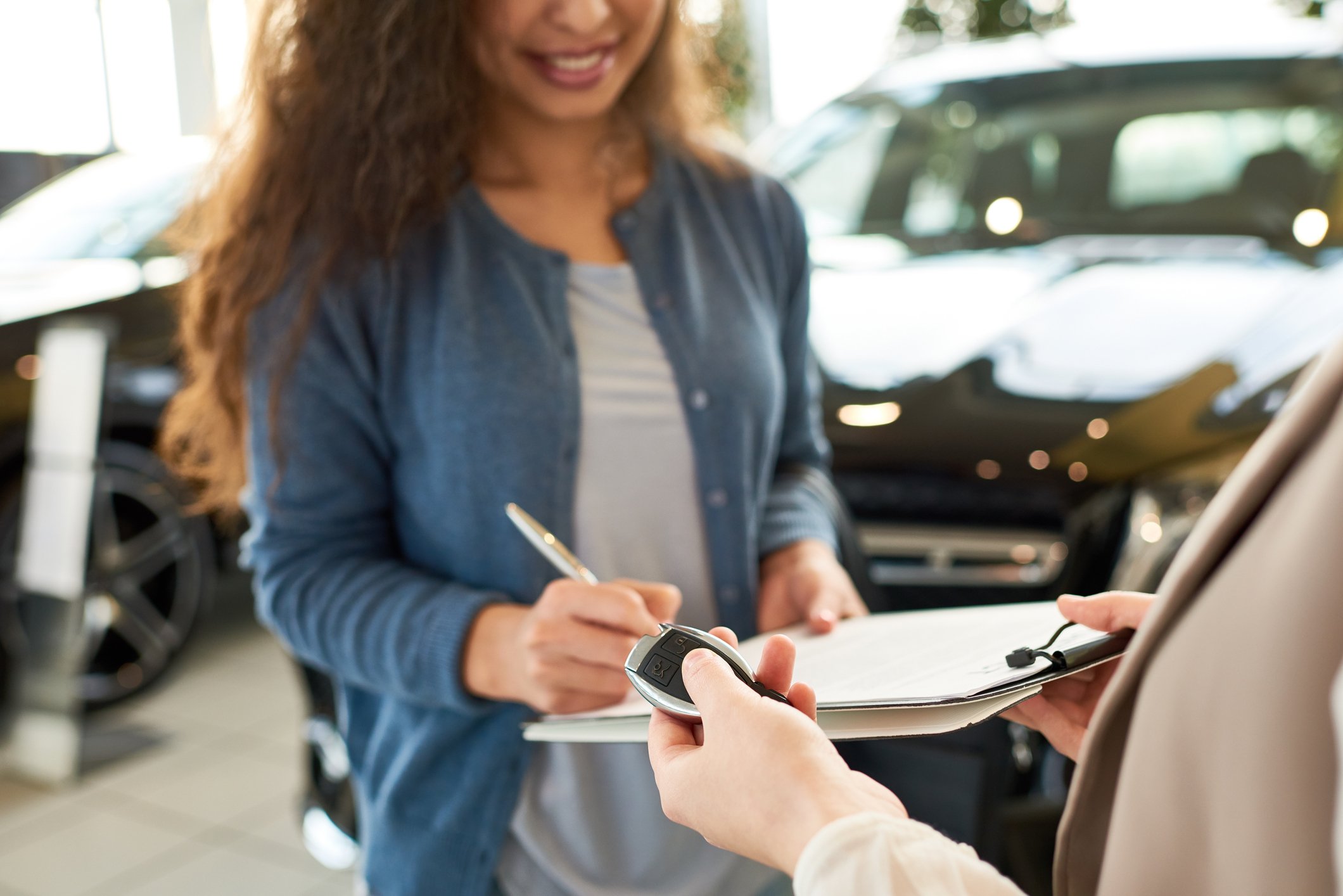 Woman signing paperwork at car dealership.