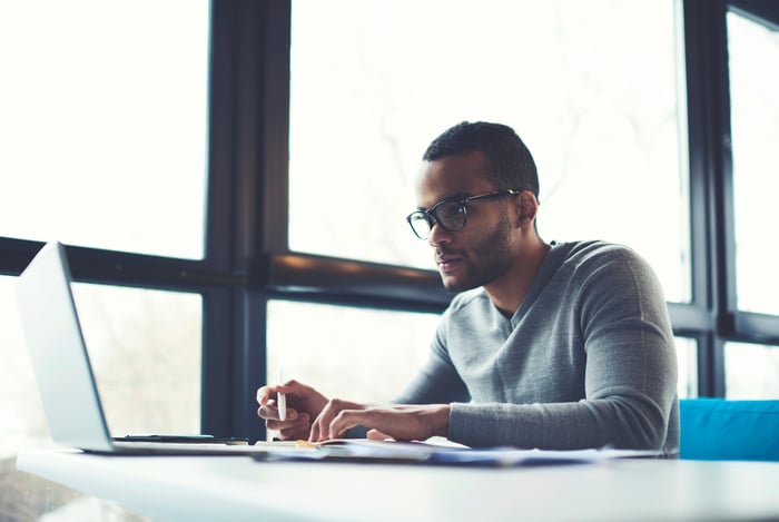 Student working at a laptop in front of several large windows