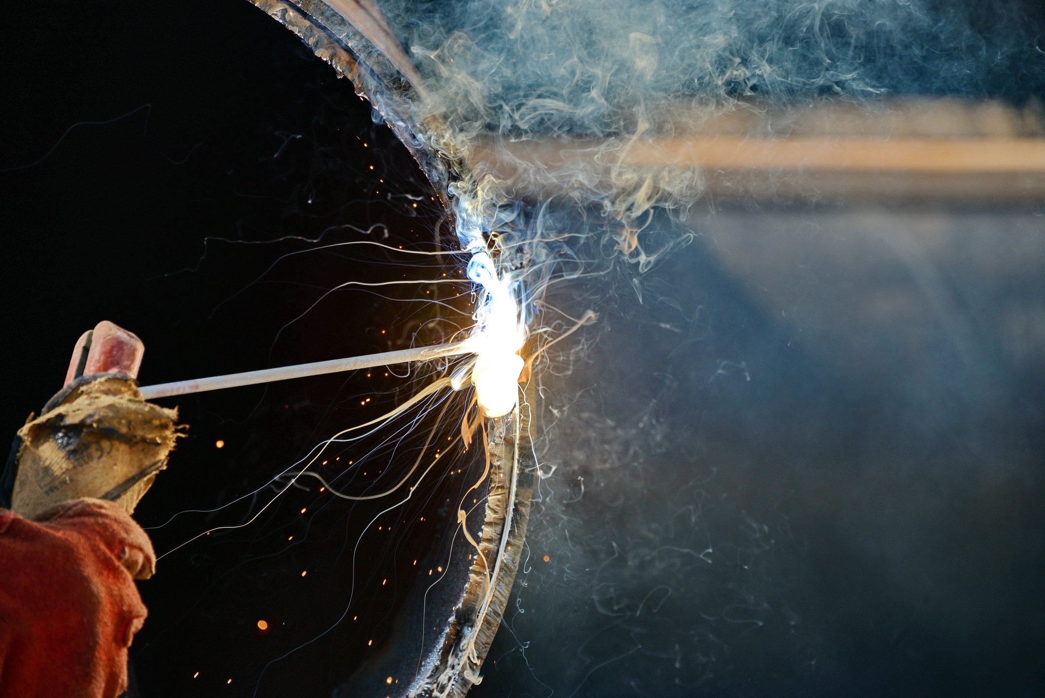 A welder working on a large pipe.