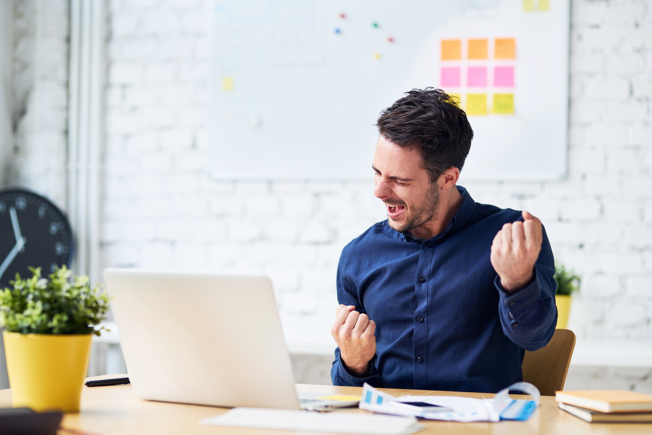 A man celebrating while sitting in front of a laptop.