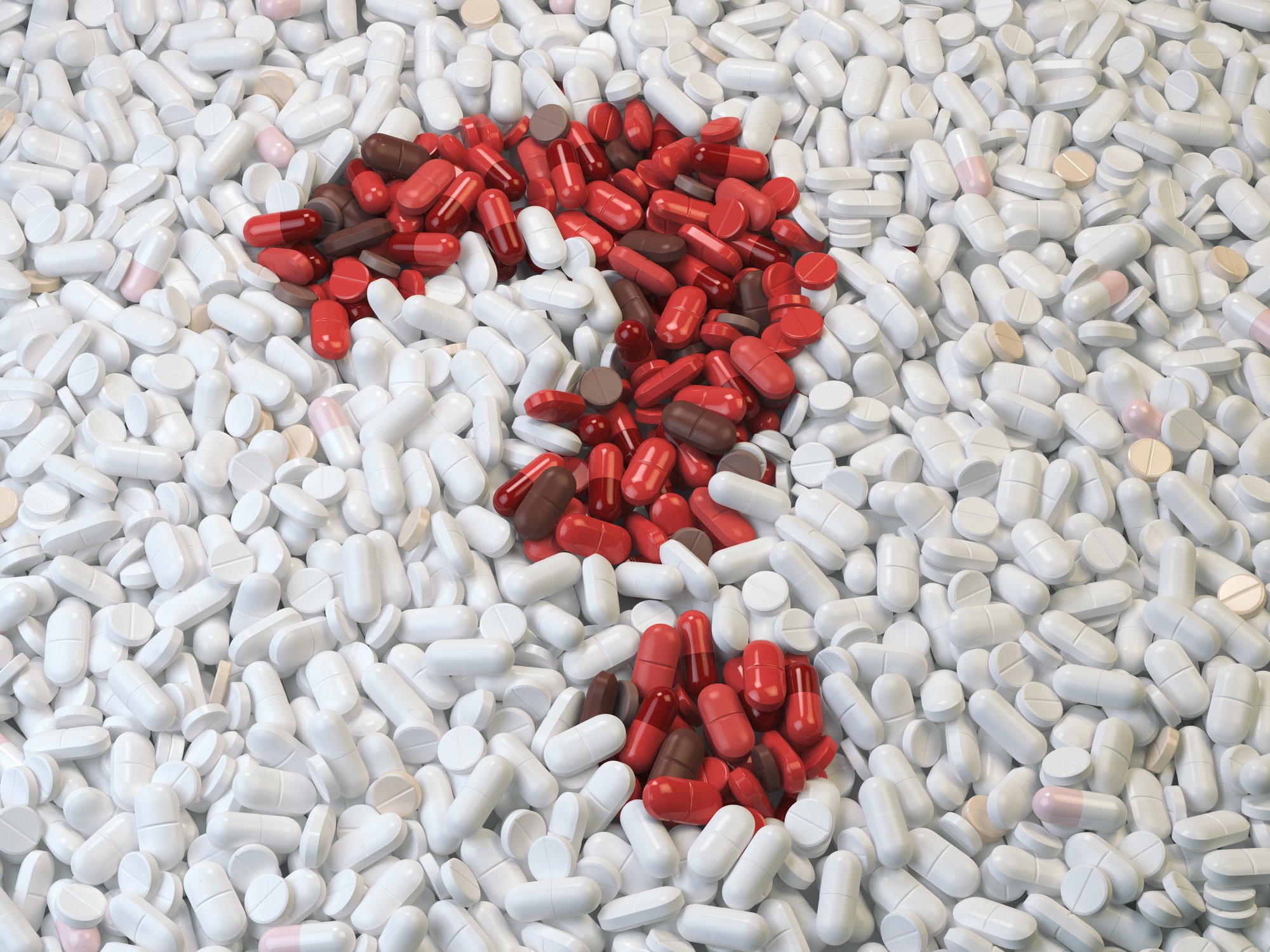 Red pills forming question mark in pile of white pills