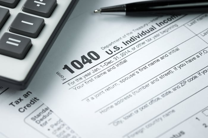 A 1040 form and pen next to a calculator