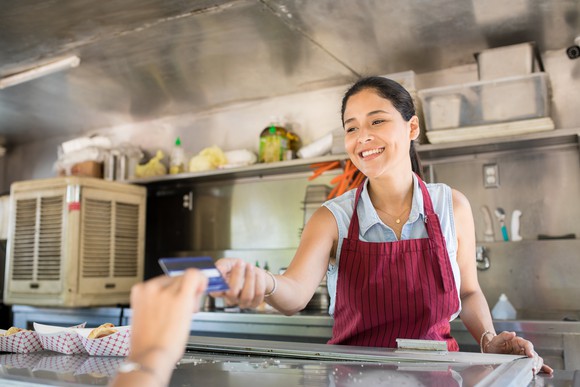 Shopkeeper accepts credit card for payment from customer.