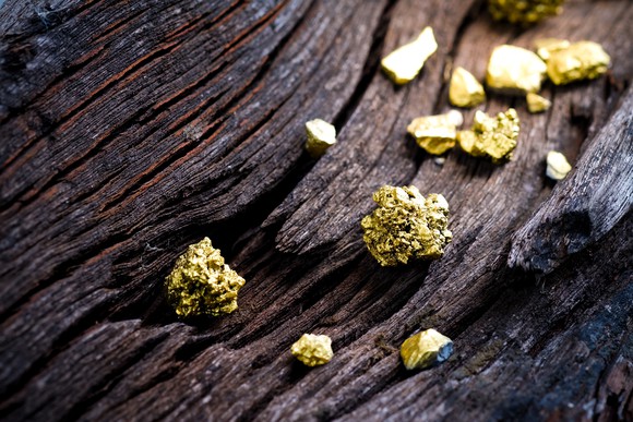 Gold nuggets on a piece of raw wood.
