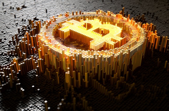 Gold-colored mosaic of bitcoin symbol against a grey mosaic background.