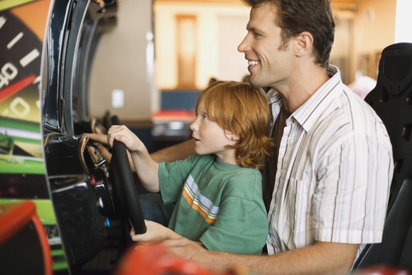 A father and son play an arcade game.