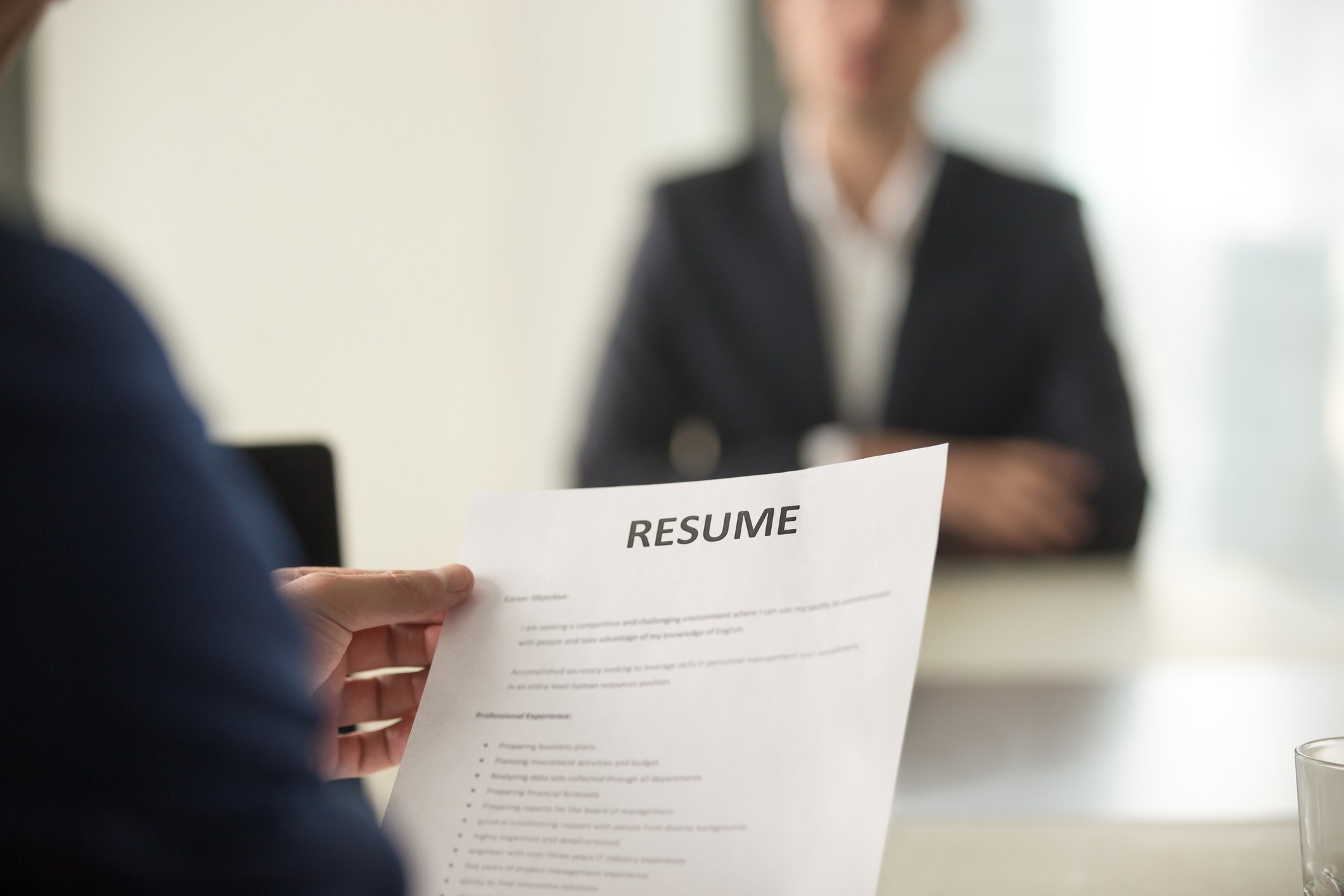 Person holding a resume while sitting across from someone in a business suit