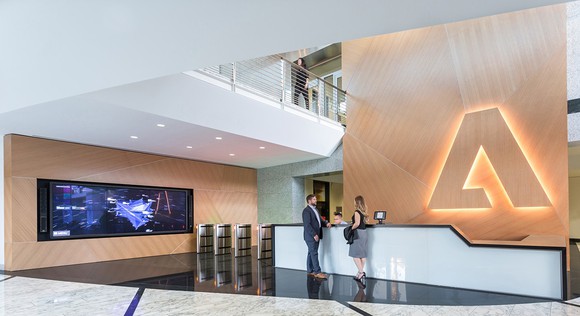 Adobe headquarters reception desk with glowing Adobe logo in the background.
