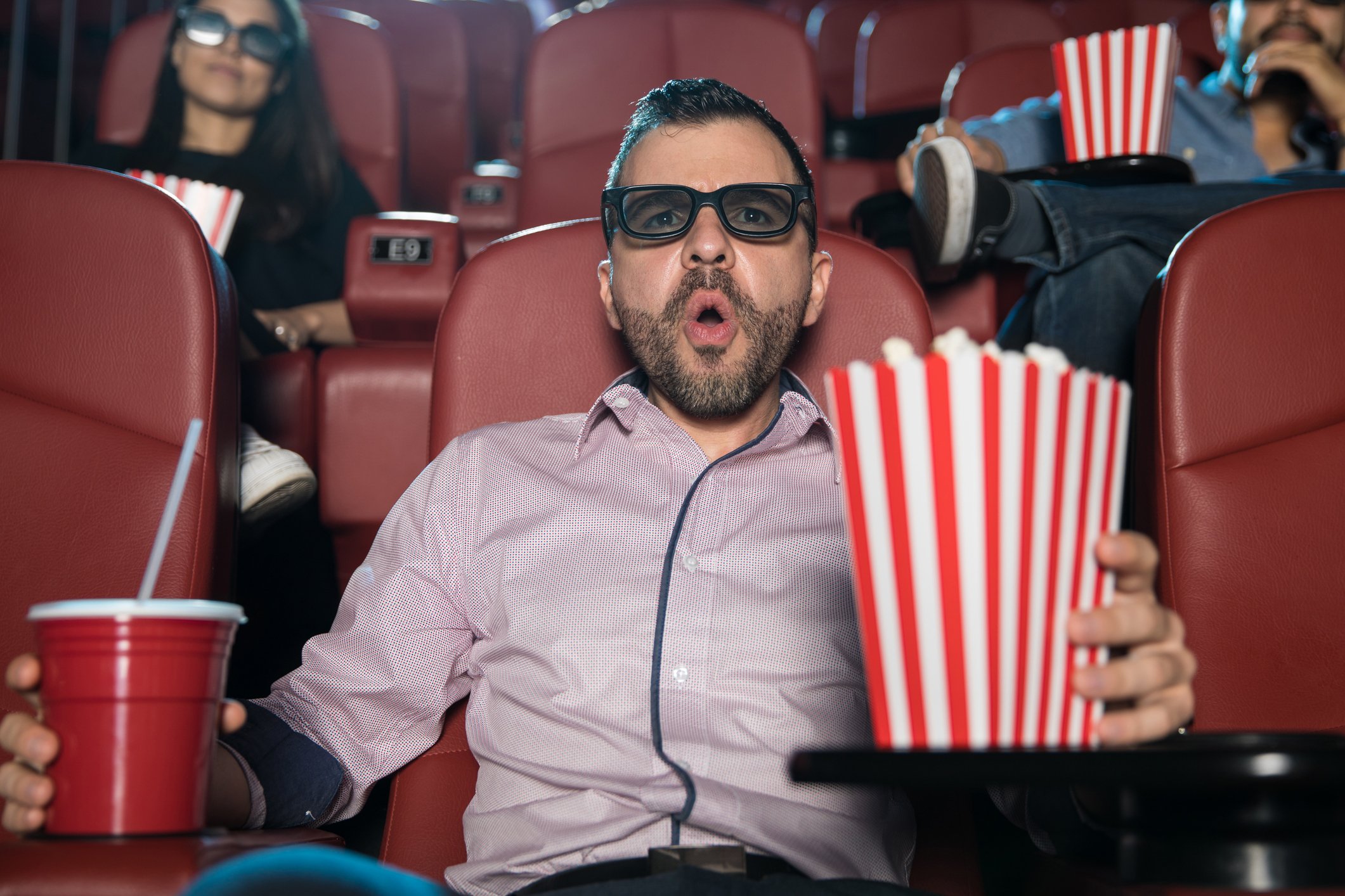 Man holding popcorn and soda and going "ooh!"
