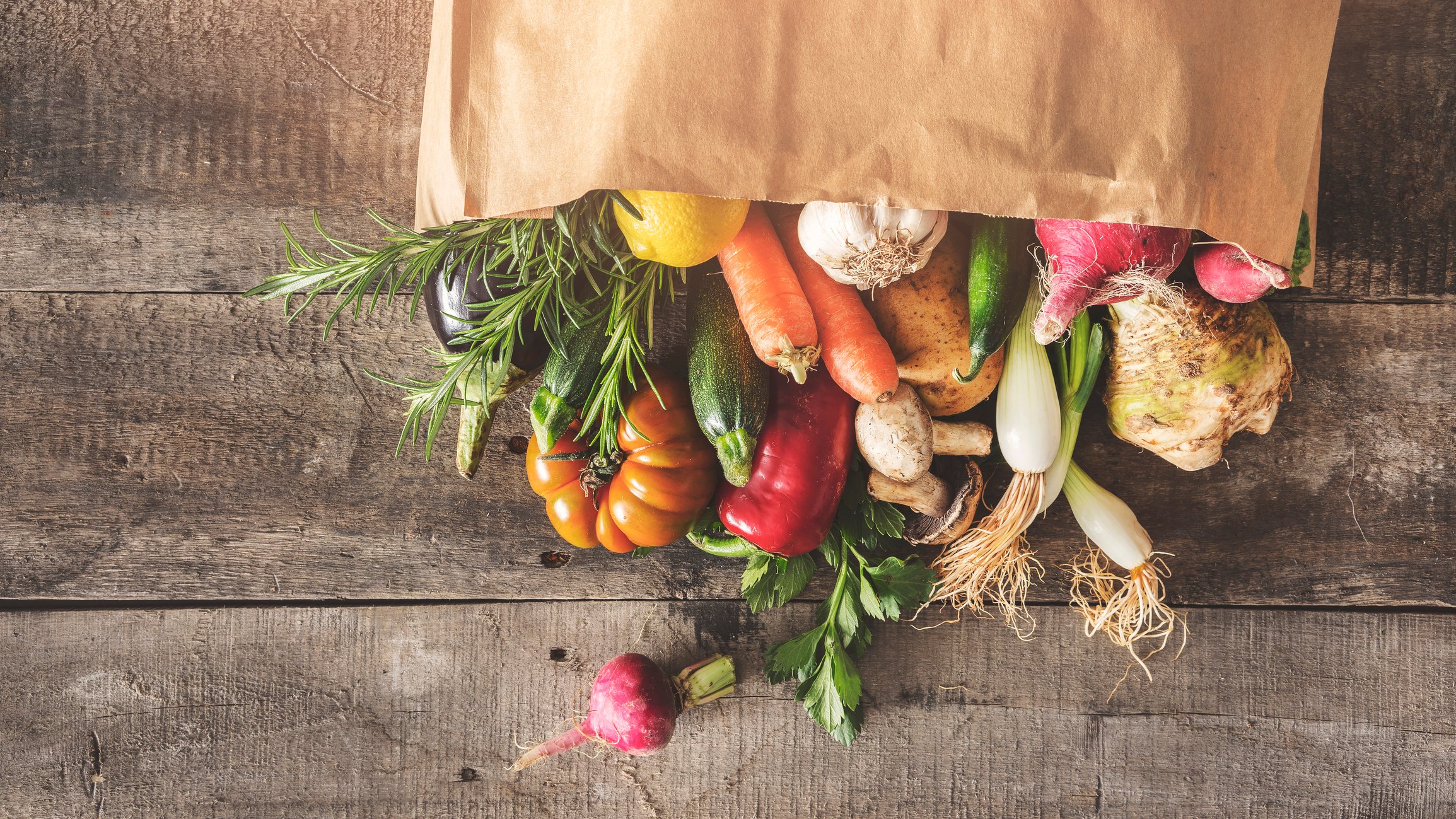 A bag of fresh vegetables spilling out on a table.