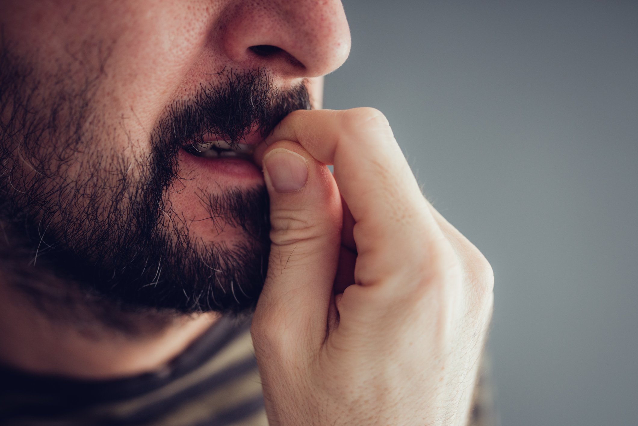 Close-up of a man biting his nails.