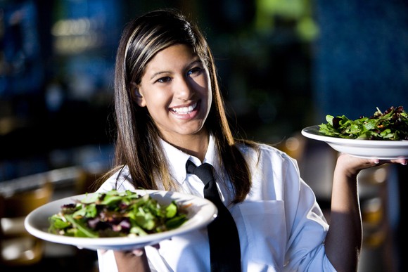 A waitress carrying salads in bowls.