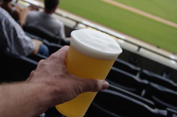 Man holding cup of beer a ballpark