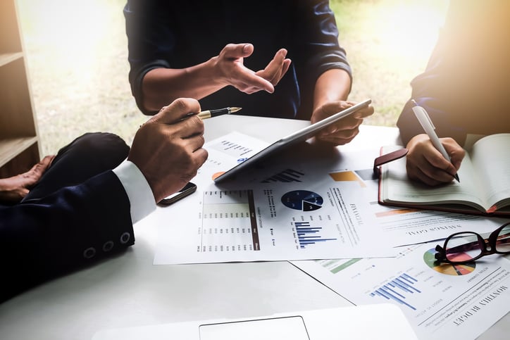 Three people sitting around a table poring over financial documents.