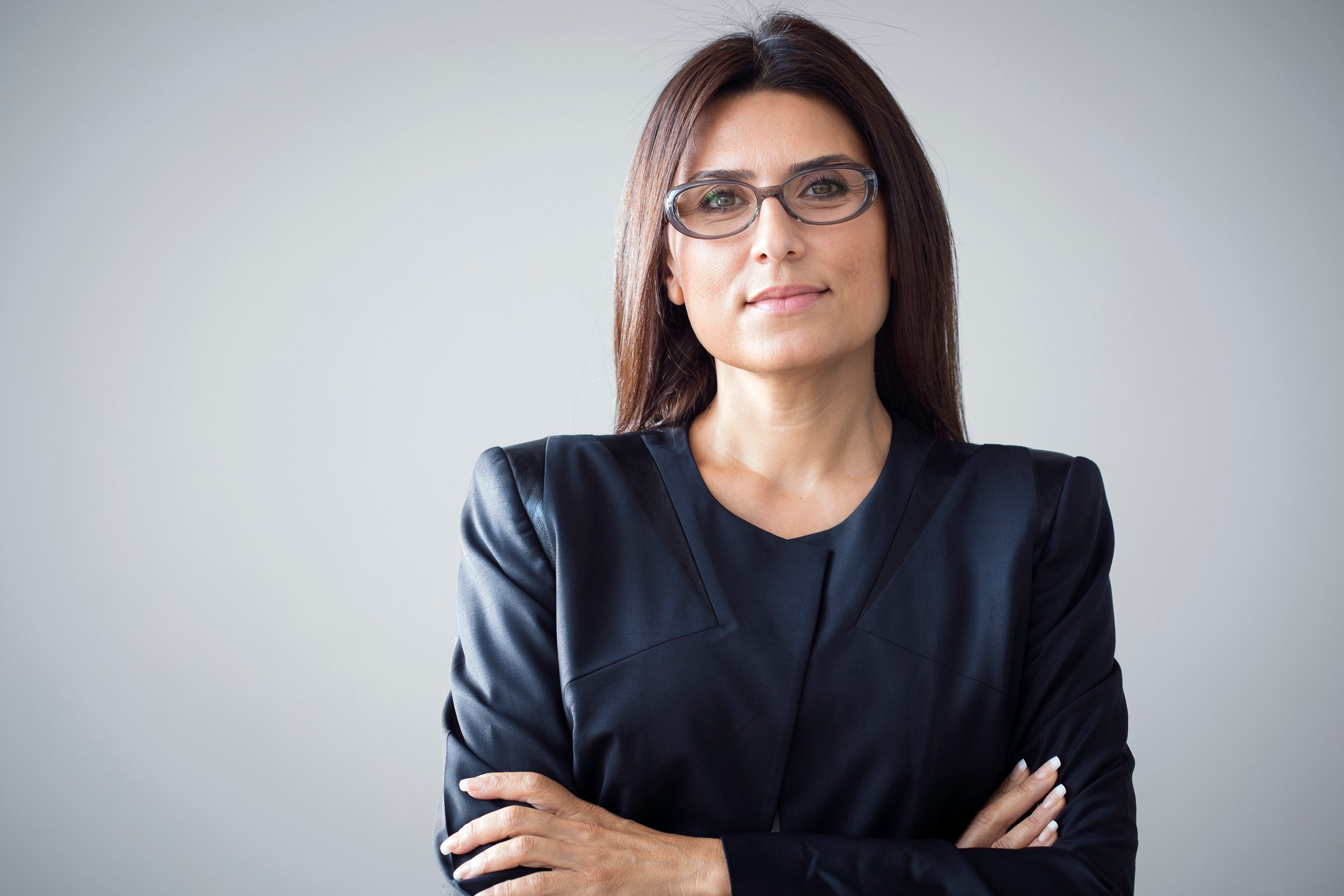 Smiling woman in business suit with arms crossed.