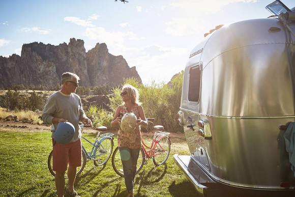 Husband and wife standing with bicycles near an Airstream RV.