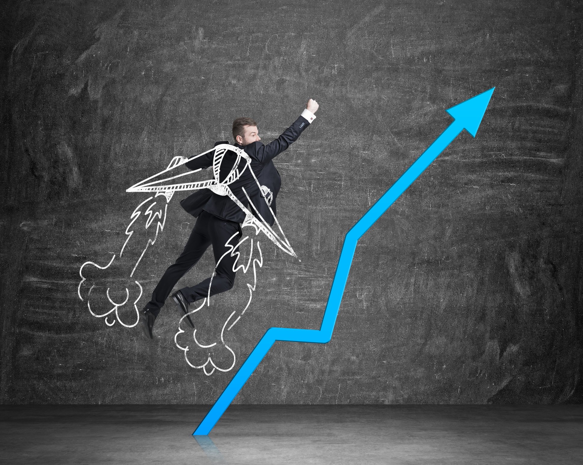 Man in a suit with chalk-drawn wings appears to be soaring, next to a blue line chart pointing up.