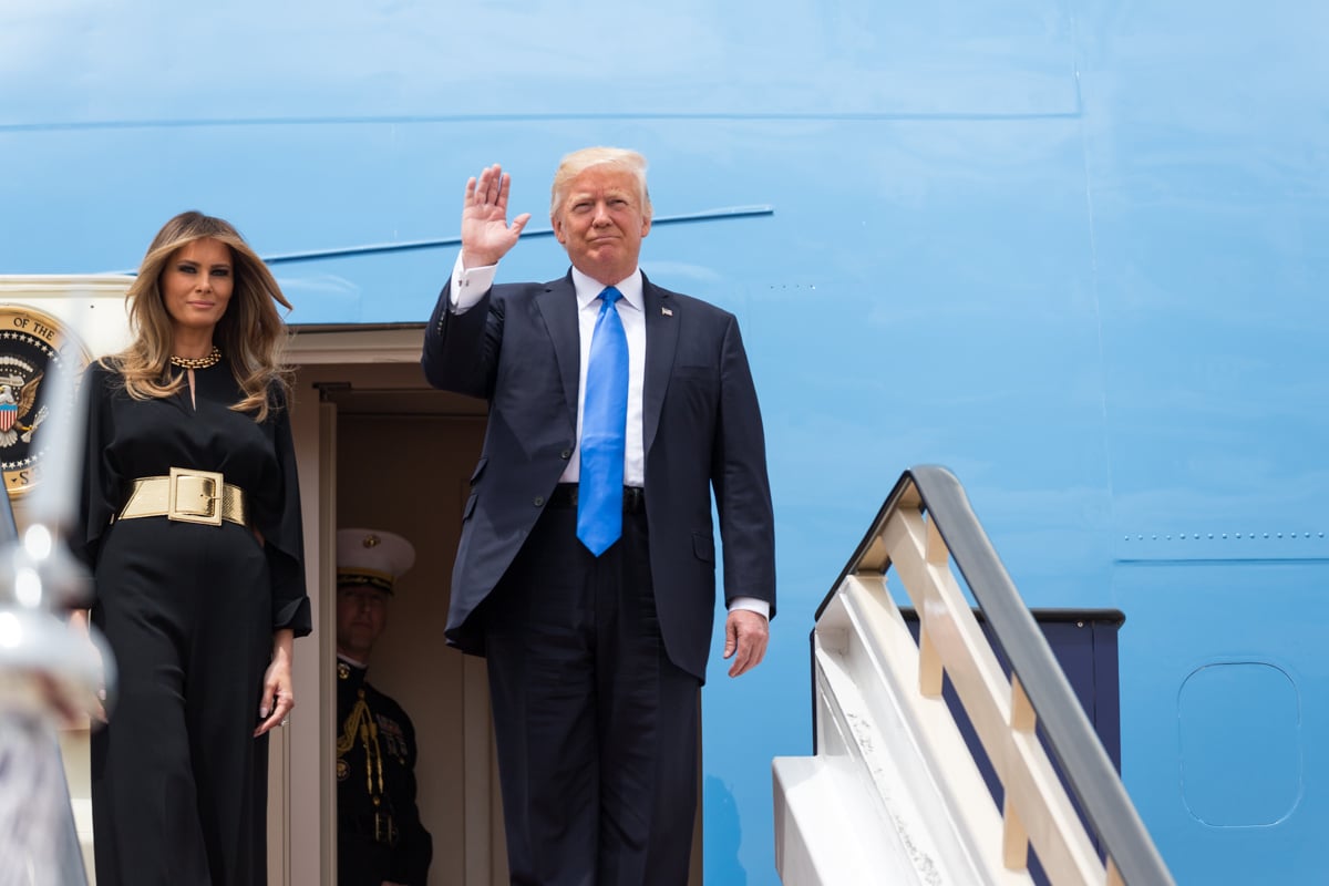 President Trump waving to reporters before entering Air Force One, with First Lady Melanie Trump by his side. 