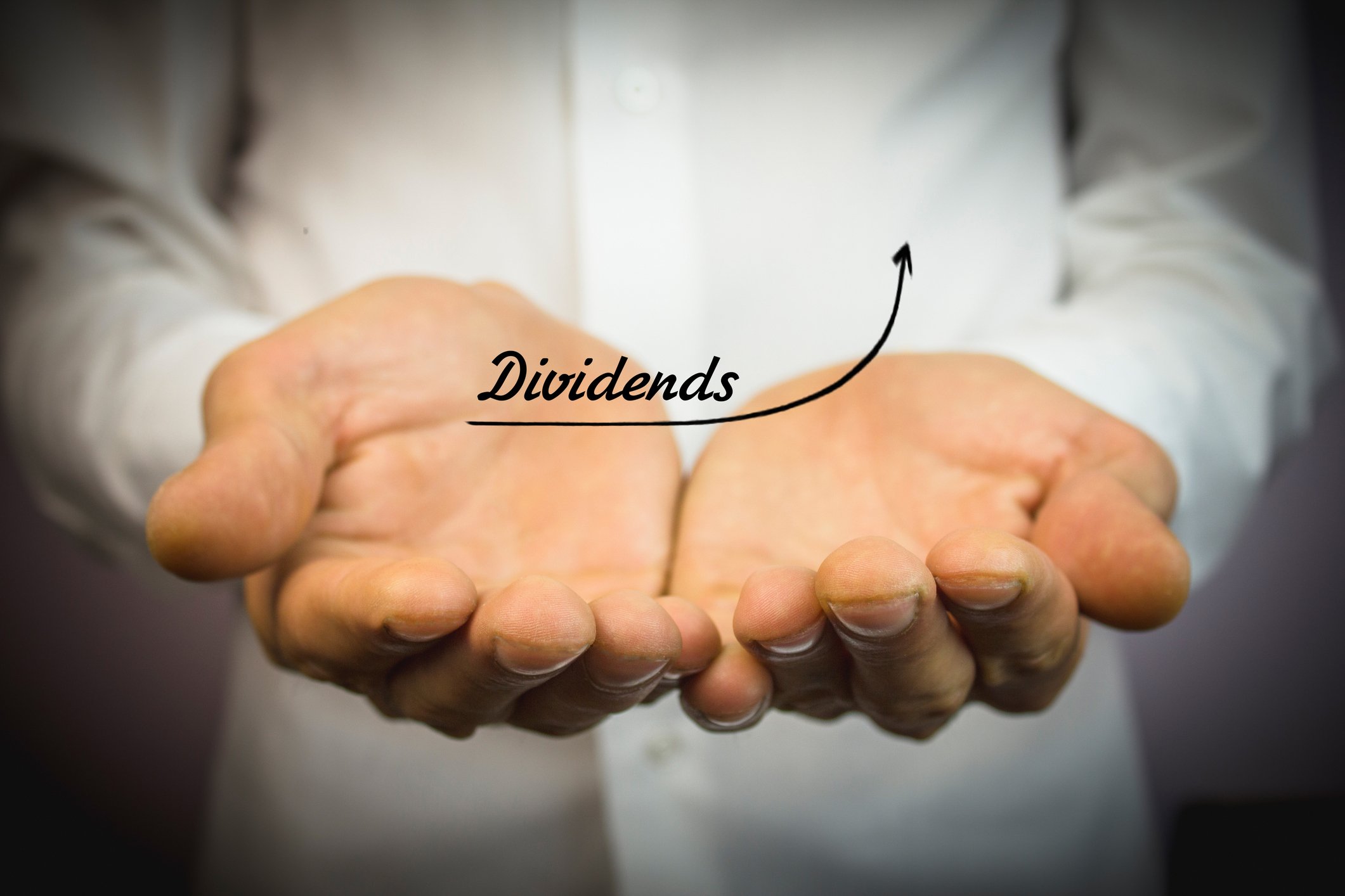 Man holding out his hands with the word Dividend written above it with an arrow indicating growth
