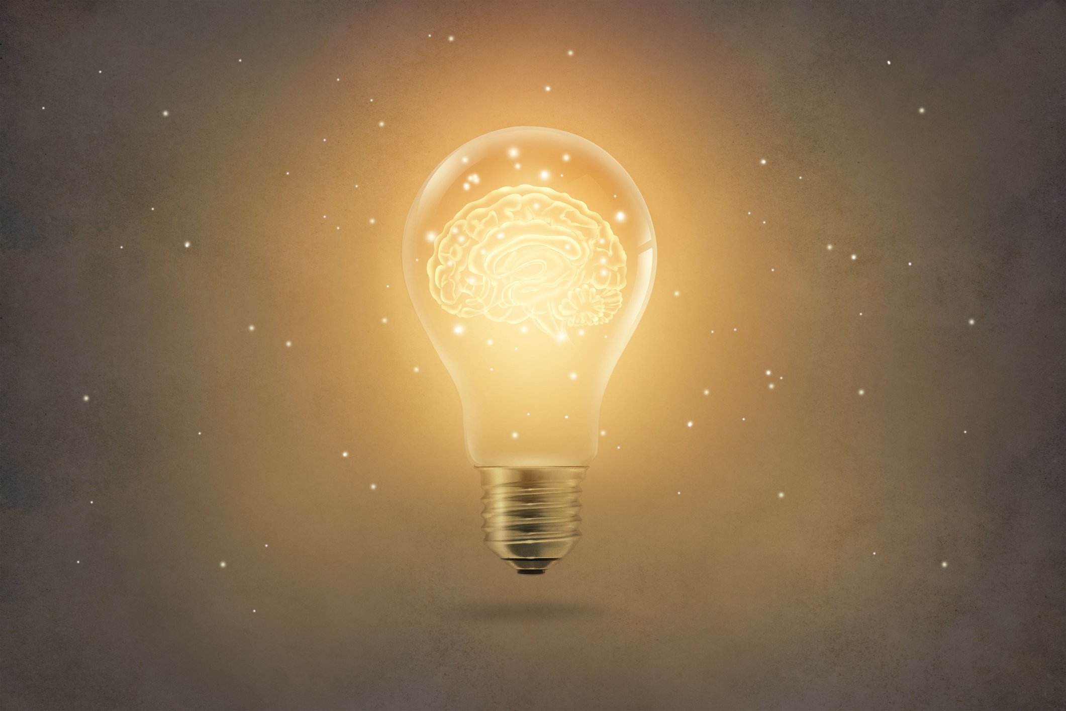 Golden brain glowing inside a light bulb on paper texture background