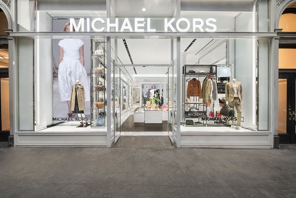 Kors storefront with gray trim and bright white interior.