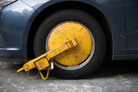 A yellow metal boot on the wheel of a car