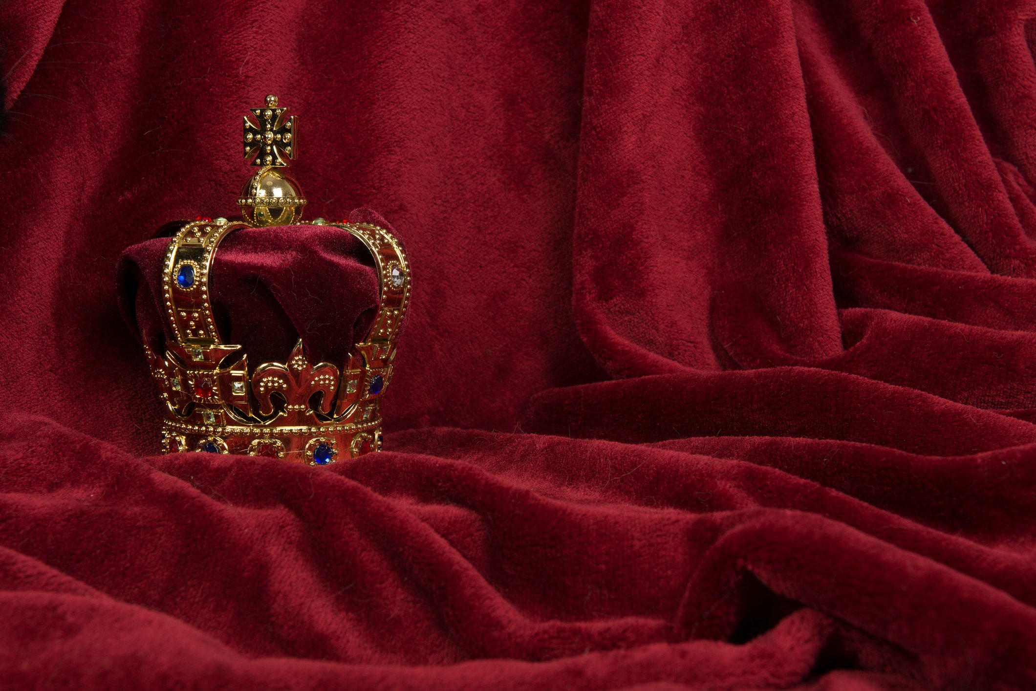 A crown sitting on a red velvet background.