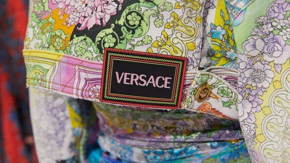 A close-up of a Versace label stitched to a piece of multicolored clothing.