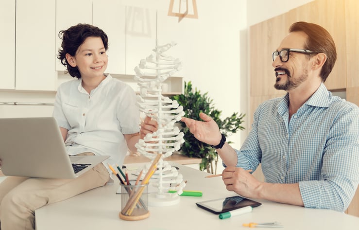 A man teaching a child about a DNA model.
