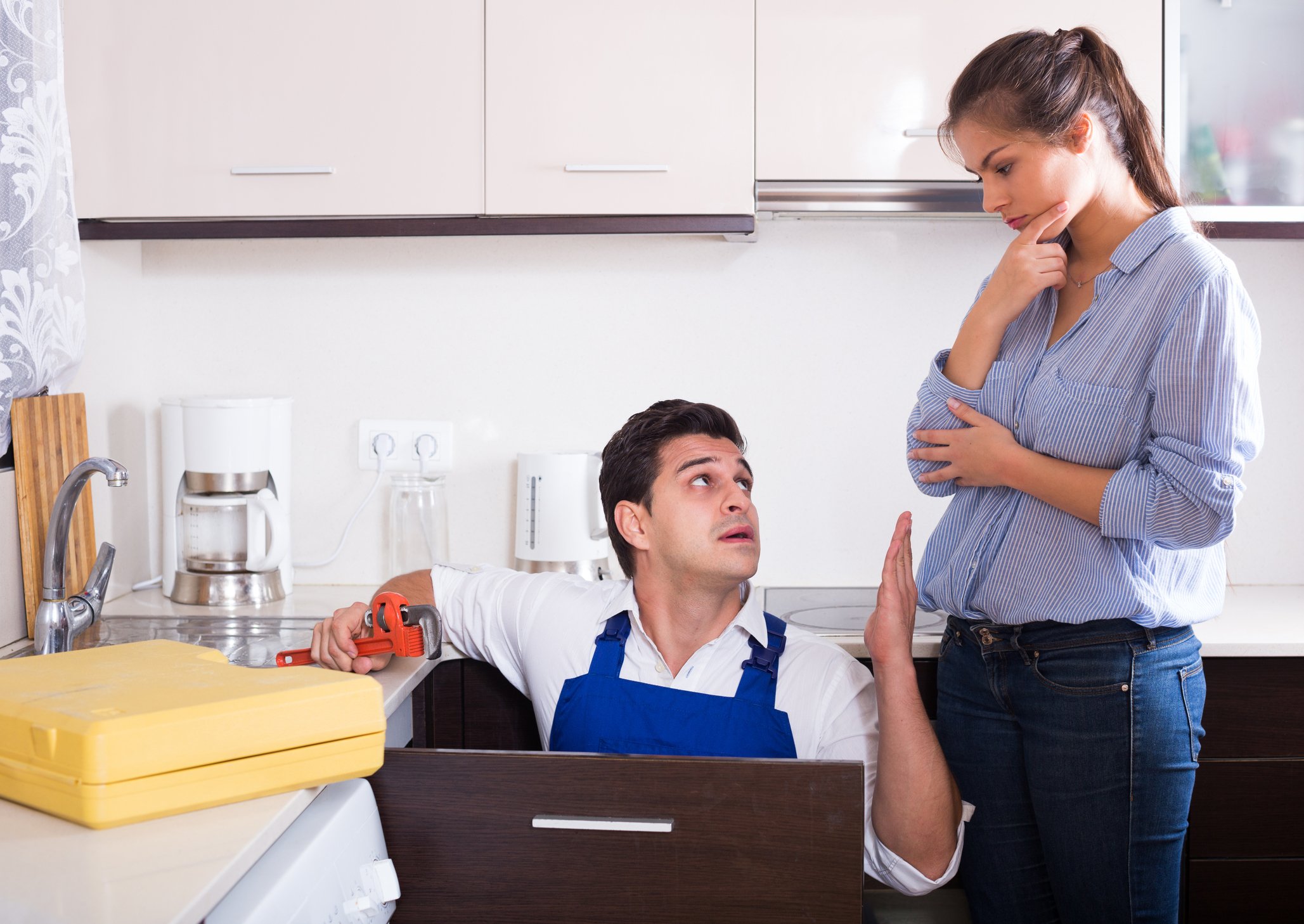 Man holding a tool, talking to woman in a kitchen