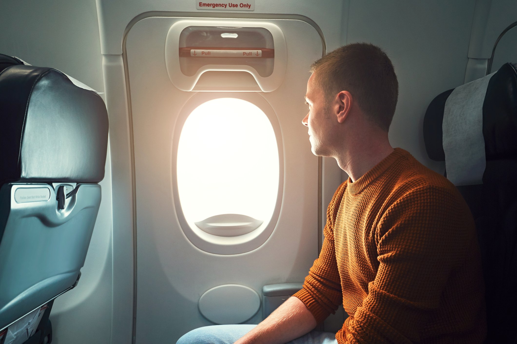 A man looking at an airplane's window exit