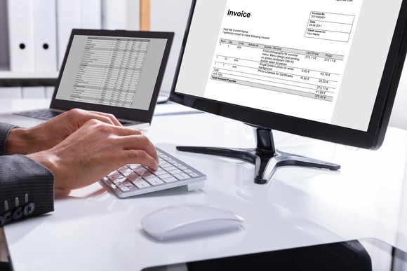 A businessman types an invoice on a computer.