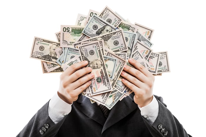 Businessman holding up a lot of cash in front of his face