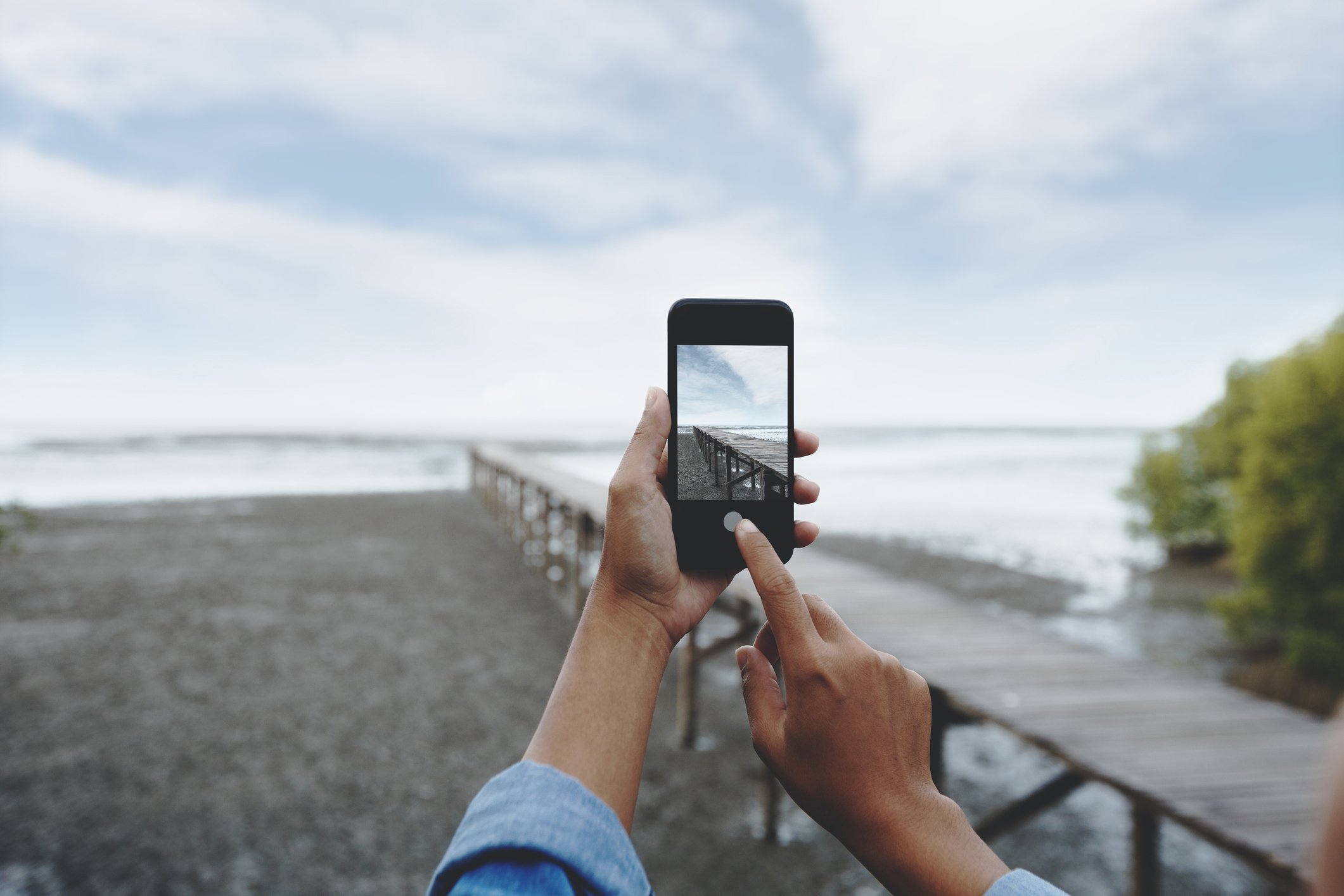 A person taking a photo of the a dock and shore.