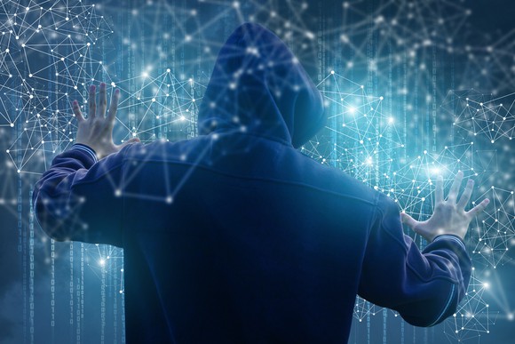 A hooded hacker inside a network of information.