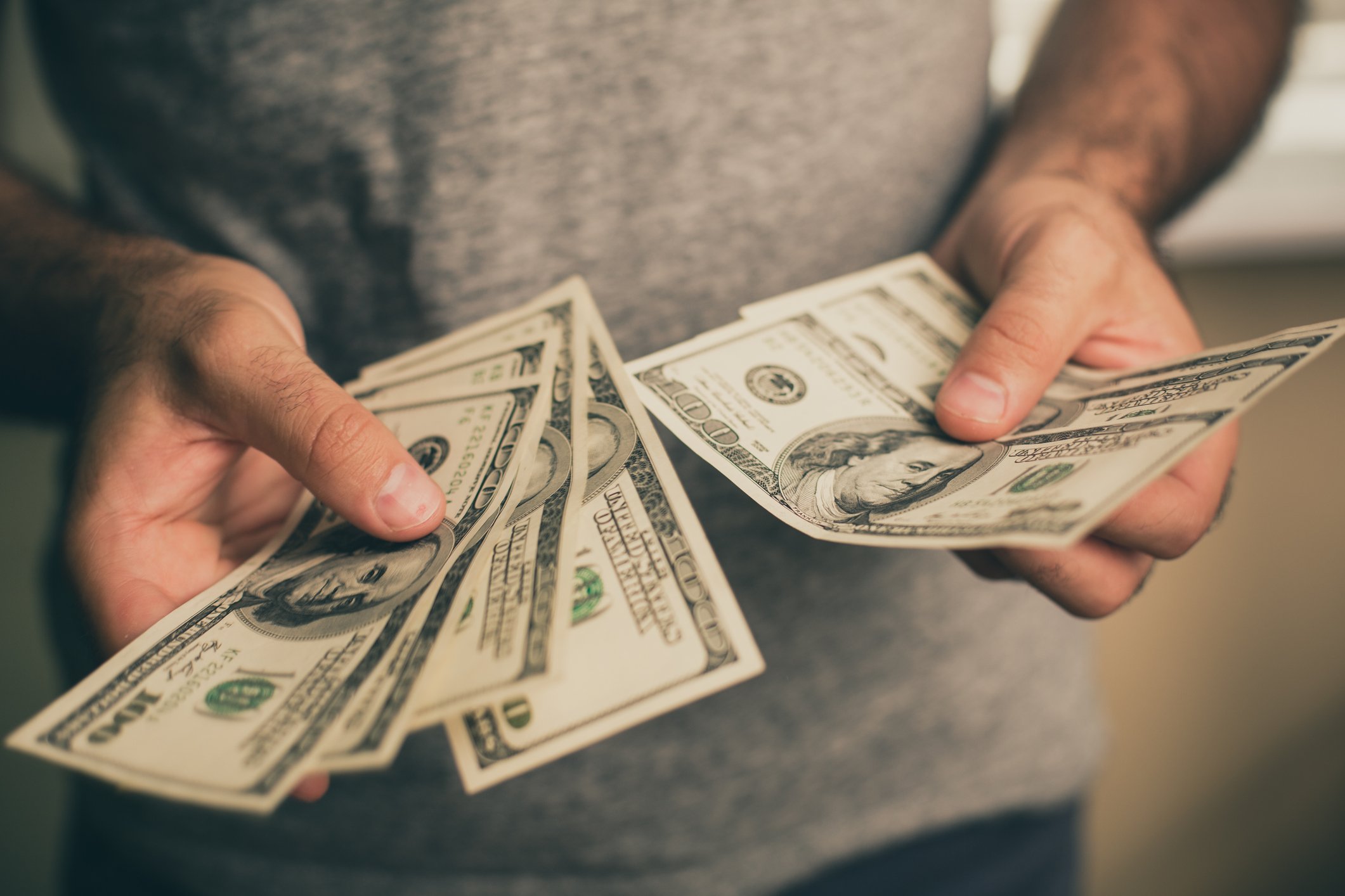 A man holds several $100 bills in his hands.