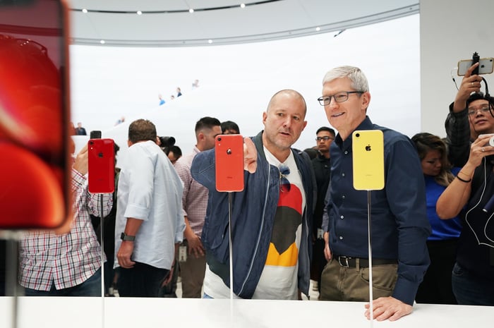 Apple executives Jony Ive and Tim Cook looking at iPhone XR smartphones.