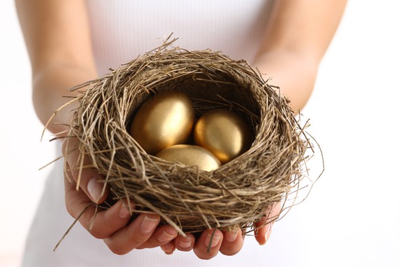 Hands holding nest with three golden eggs