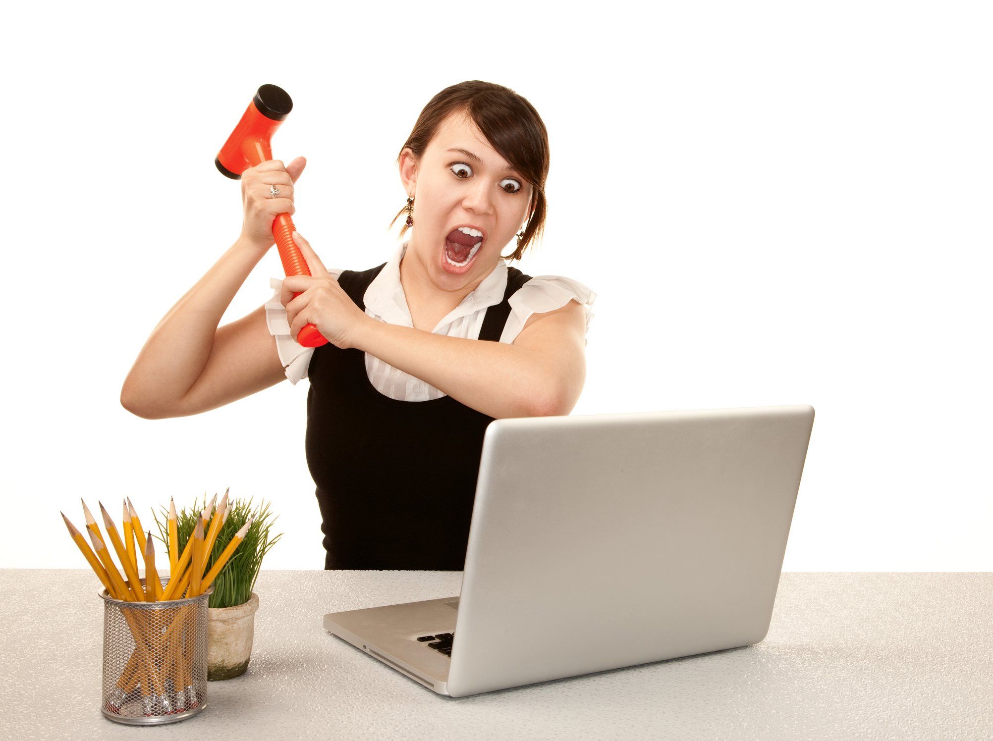Businesswoman screaming and swinging an orange mallet at her laptop.
