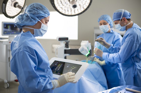 Doctors and nurses in blue scrubs performing robotic surgery using Mazor technology.