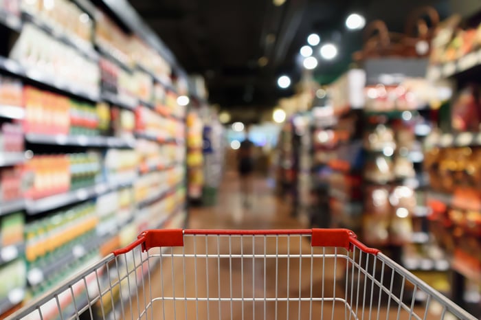 A shopping cart in a supermarket aisle.