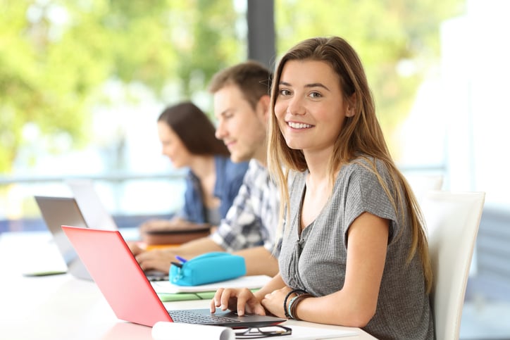 Three young adults -- two women, one man -- sitting at a table with their laptops open.