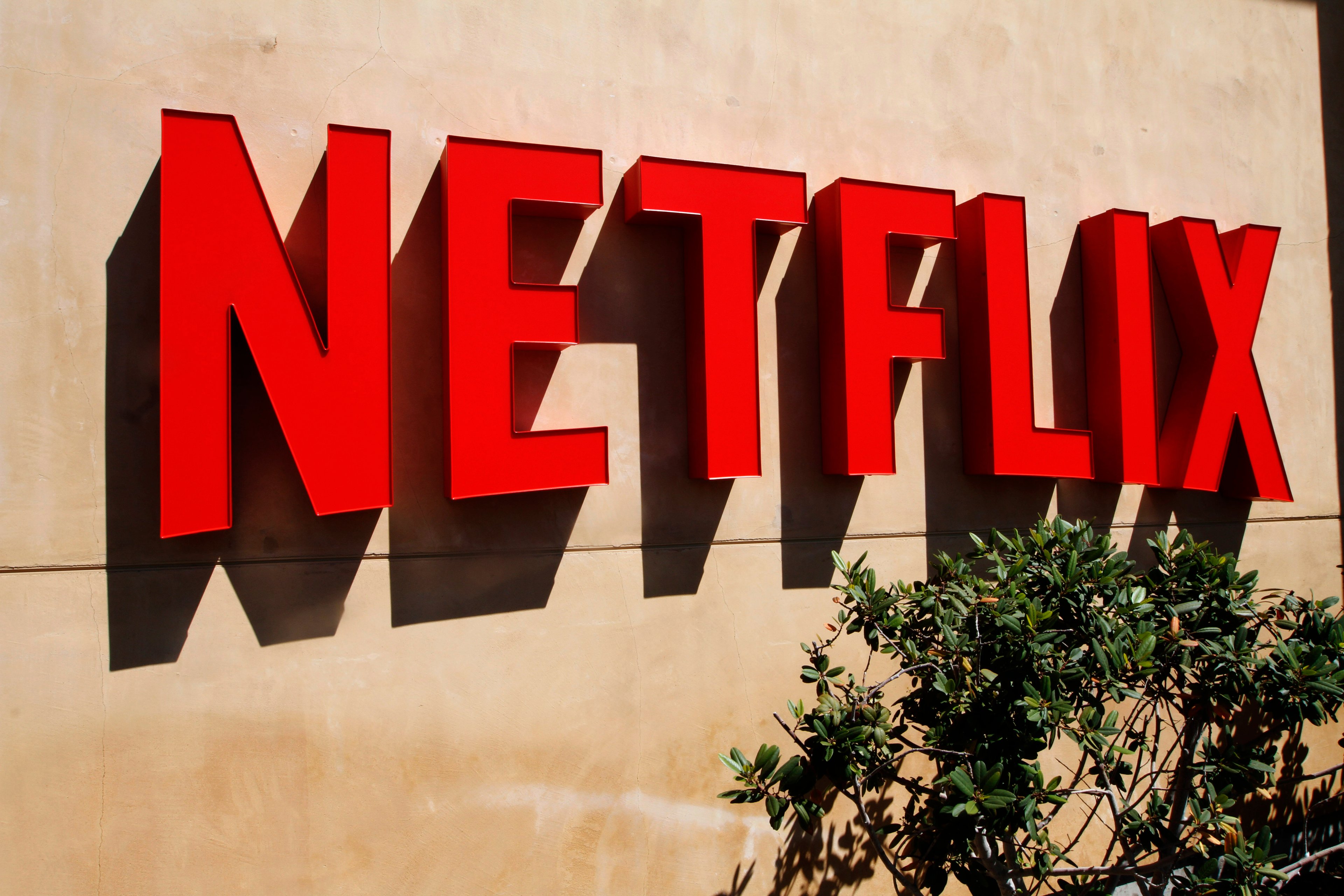 Red netflix logo on a stucco wall outside the company's headquarters.