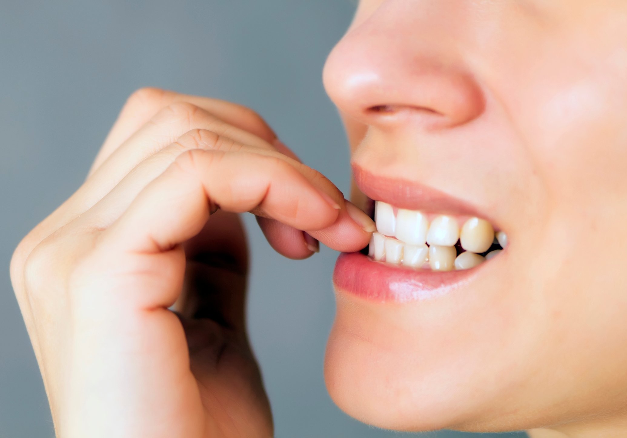 Close-up of a woman biting her nails.