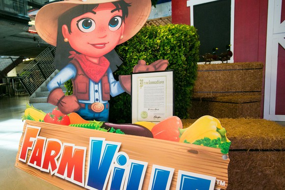 Cutout poster of FarmVille logo and character in front of a display set up in a mall.
