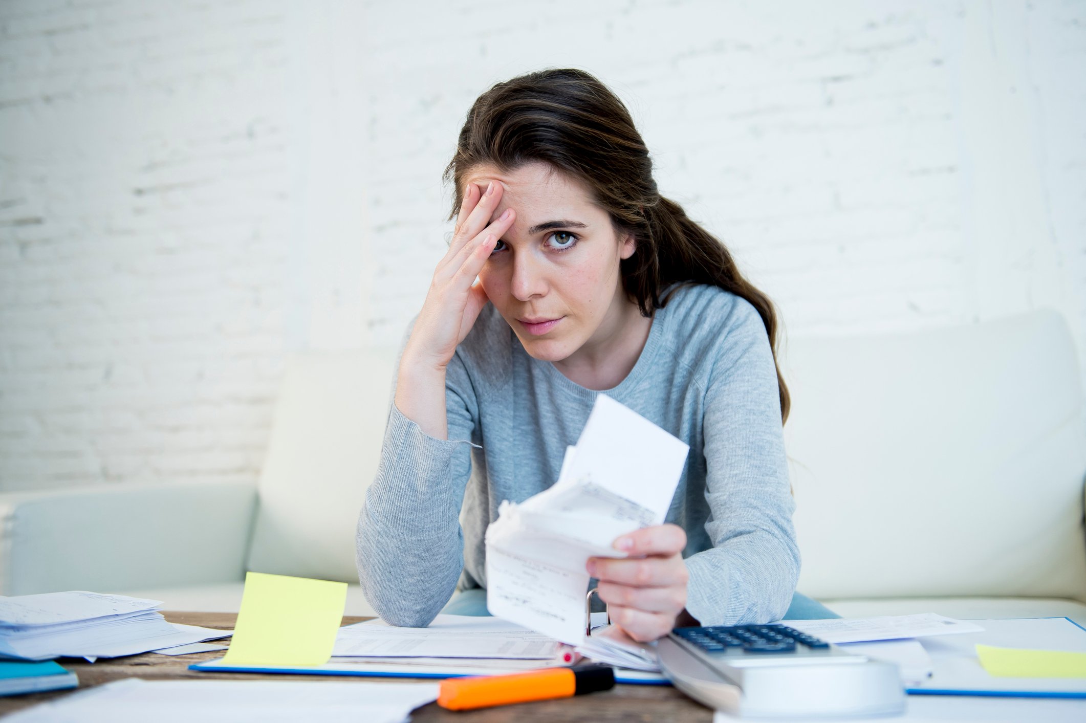 Young woman holding her head while going through paperwork.