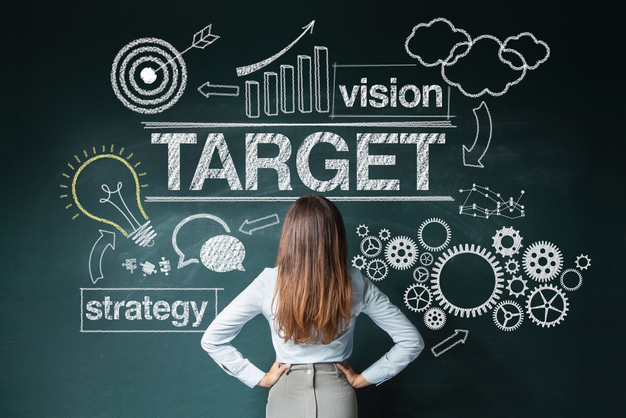 A woman looks at a blackboard with writing on it.