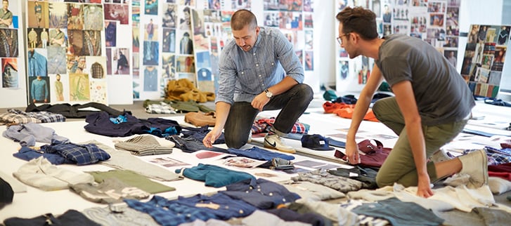 Two employees with several pairs of Gap pants laid out before them. 
