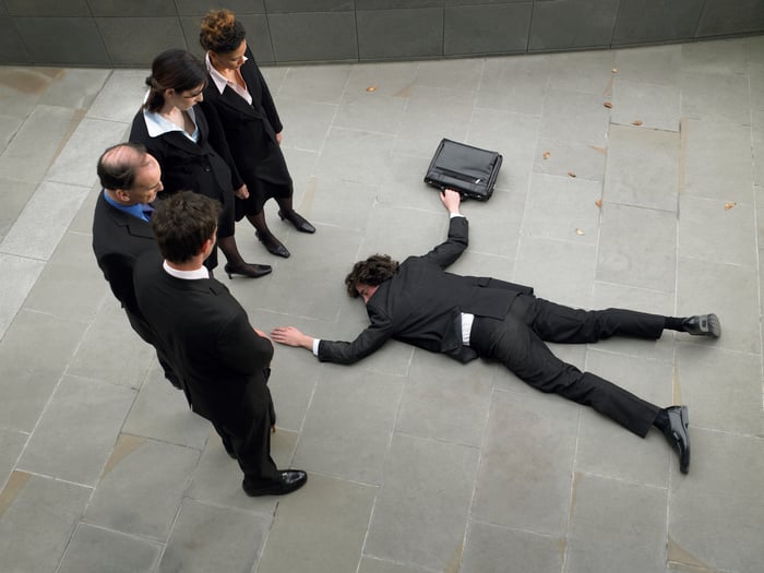 Businessman lying face down on a sidewalk while holding a briefcase.
