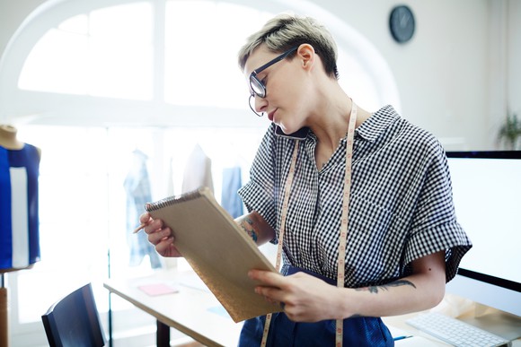 A woman holds a clipboard while talking on the phone.